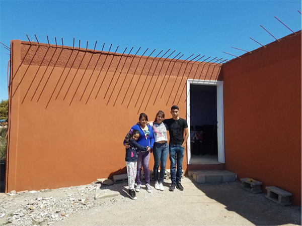 Dayra and family pose in front of their newly completed home, painted orange