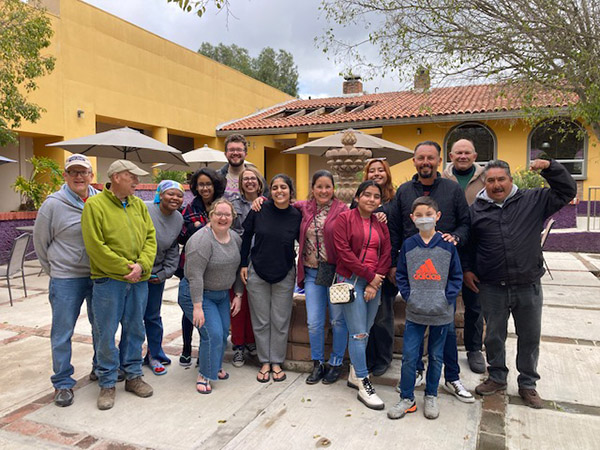 A volunteer group and Eduardo pose together in the courtyard of la posada