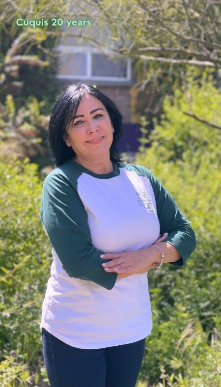 Cuquis in an Esperanza shirt in the sun with text that says her name and "20 years"
