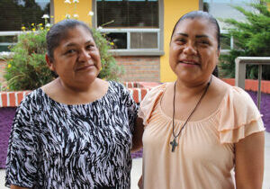 Adult mother and daughter of Casa Mil hug and pose in front of la posada