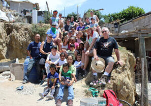 Eindelisa's family, community, and volunteers pose together at a worksite