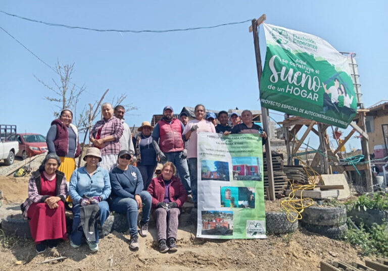 Lourdes and the Rosarito FAV pose with FAV signage and a banner that reads "Aqui se construye el sueno de su hogar" with the Esperanza logo